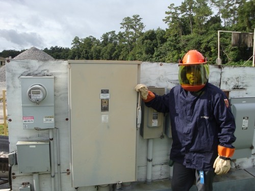 Dan House Electric electrician in full arc-flash safety gear servicing a commercial panel